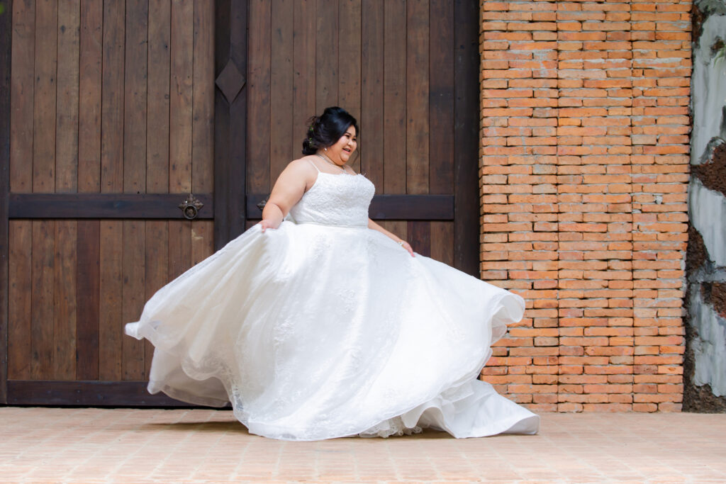 Asian bride with beautiful updo in her hair, twirling her wedding gown. Bride is in front of large, medieval looking wooden doors.