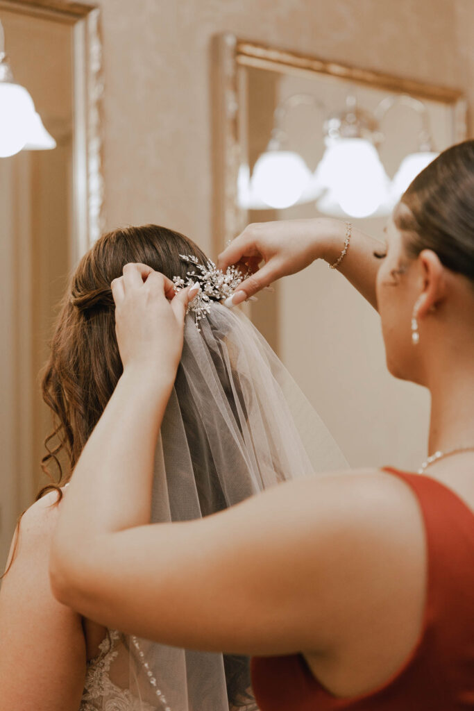 woman helping another woman try on a wedding veil at Vivid Bridal Boutique