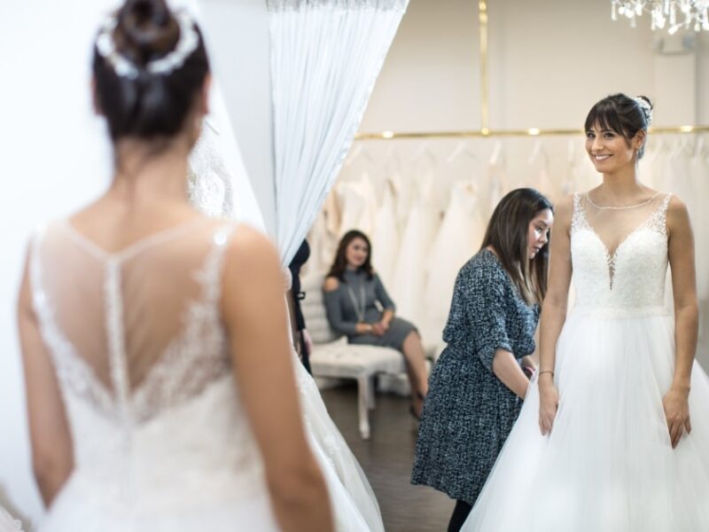 smiling bride looking at herself in the mirror wearing a wedding dress from Vivid Bridal Boutique