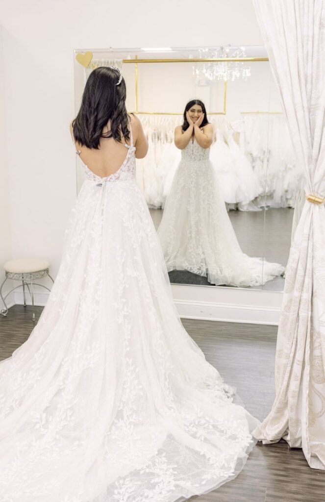 a bride looking at herself in a wedding dress in a mirror and smiling