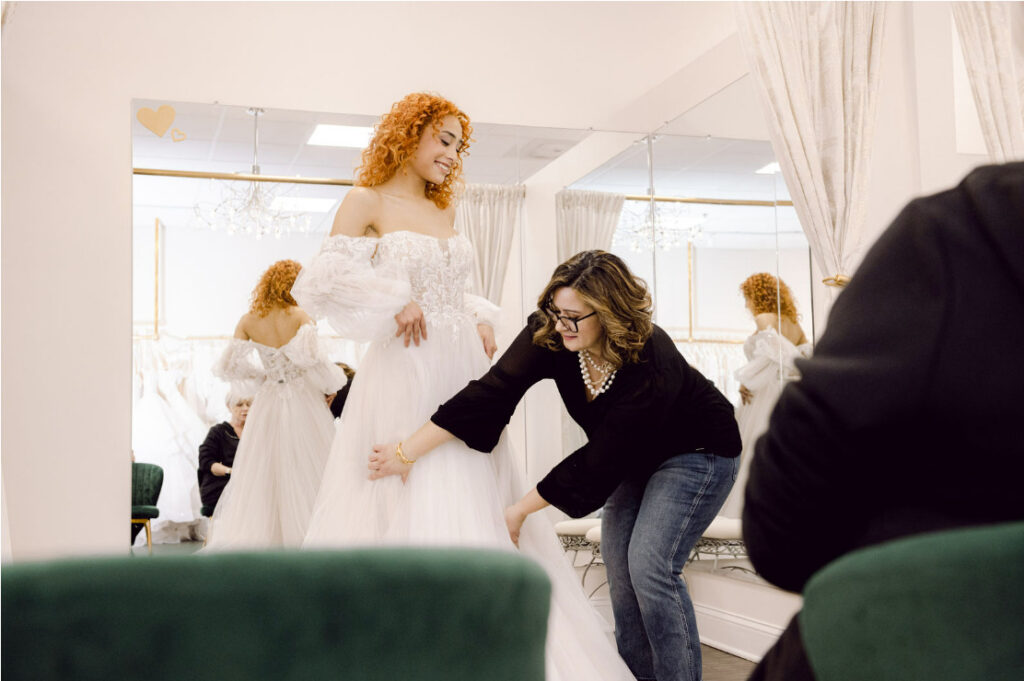 bridal stylist helping bride get fitted for wedding