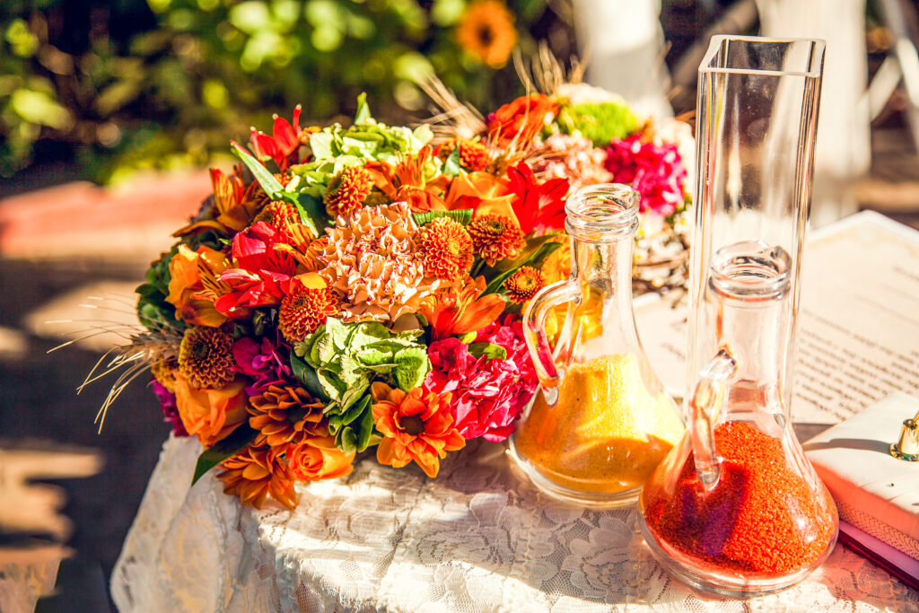 autumnal bouquet of flowers with red and orange-colored sand in glass vases
