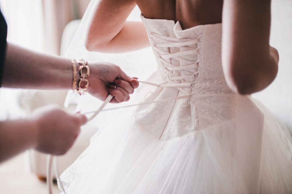woman tying the corset on a bride's wedding dress
