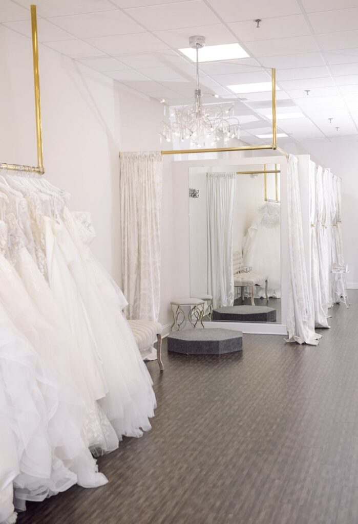 wedding dresses on a gold rack with fitting rooms in the background