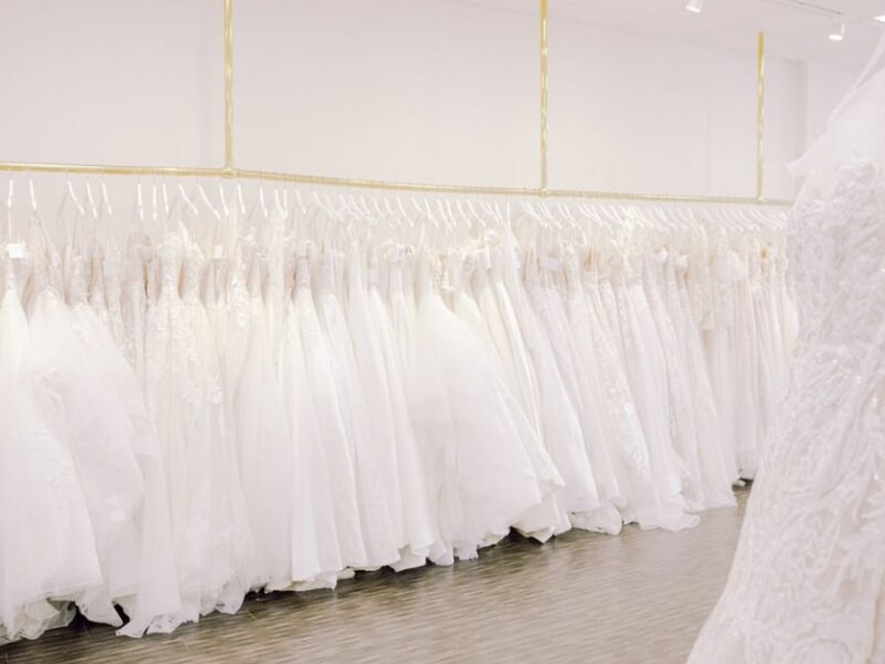 white room with beautiful wedding dresses hanging up on a gold rack