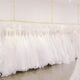 white room with beautiful wedding dresses hanging up on a gold rack